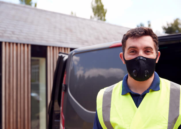 tradesmen wearing covid mask next to van tradesmen wearing covid mask next to van